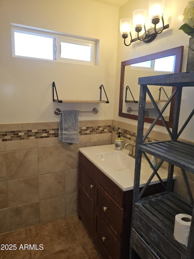 bathroom with vanity, a wealth of natural light, tile patterned floors, and tile walls