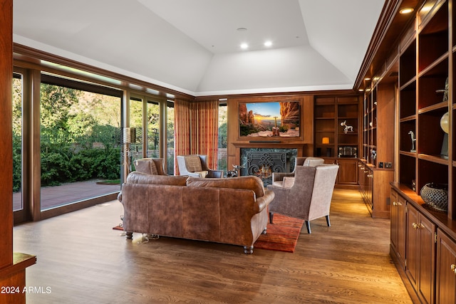 living room featuring high vaulted ceiling, a warm lit fireplace, and wood finished floors