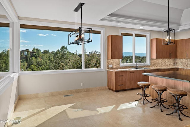 kitchen with a sink, a tray ceiling, brown cabinets, and visible vents