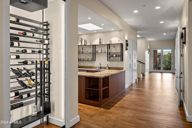 wine cellar featuring baseboards, dark wood finished floors, wet bar, recessed lighting, and a sink