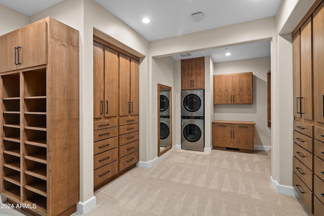 washroom with baseboards, light colored carpet, recessed lighting, stacked washer and clothes dryer, and cabinet space