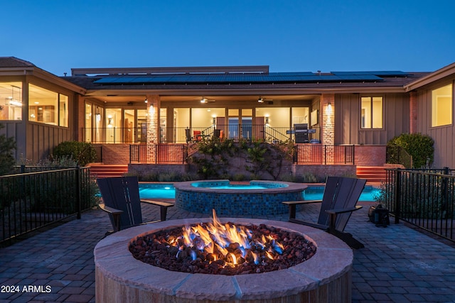 view of patio with an outdoor pool, a fire pit, stairs, and an in ground hot tub