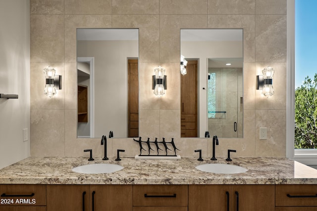 bathroom with a sink, a shower stall, and double vanity