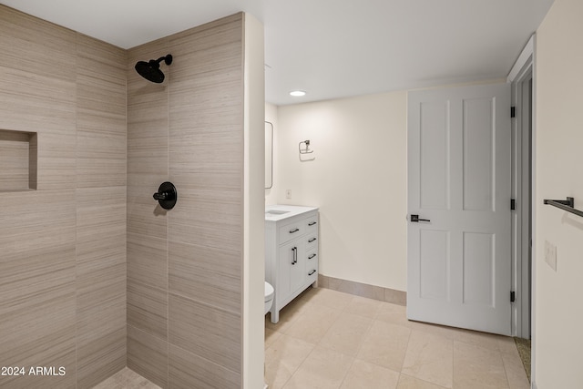 full bathroom featuring a tile shower, tile patterned floors, vanity, and baseboards