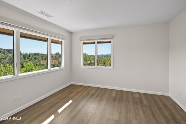 unfurnished room featuring visible vents, baseboards, and wood finished floors