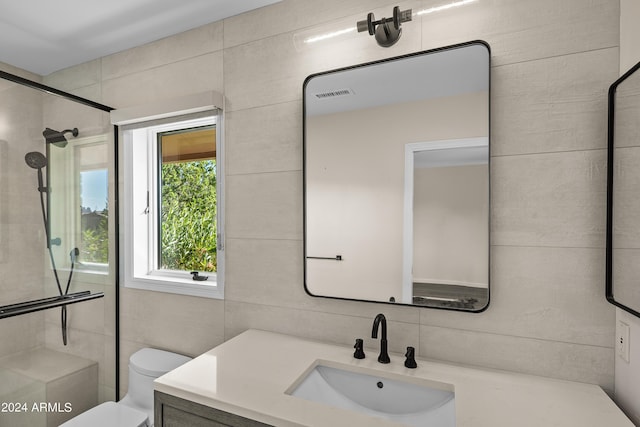 bathroom featuring tasteful backsplash, visible vents, toilet, tiled shower, and vanity