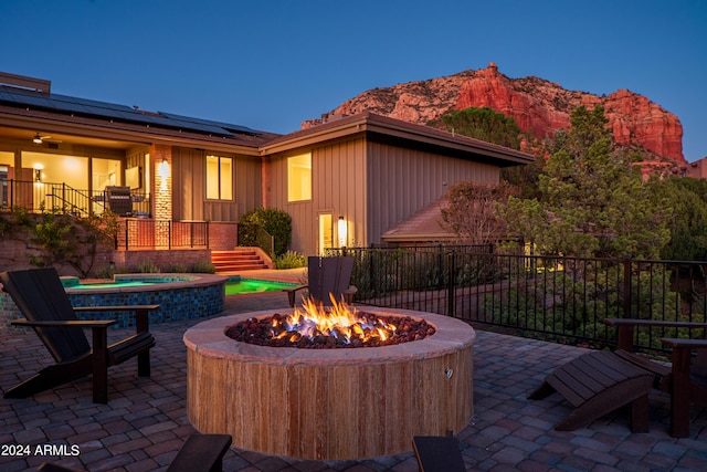 view of patio with a fire pit, fence, stairs, an outdoor hot tub, and a mountain view