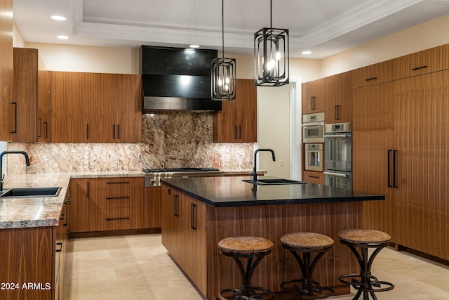 kitchen featuring a sink, a tray ceiling, range hood, and brown cabinetry