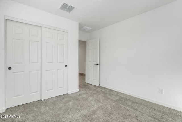 unfurnished bedroom with light colored carpet and a closet