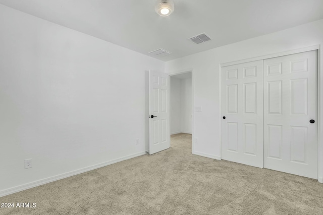 unfurnished bedroom featuring light colored carpet and a closet