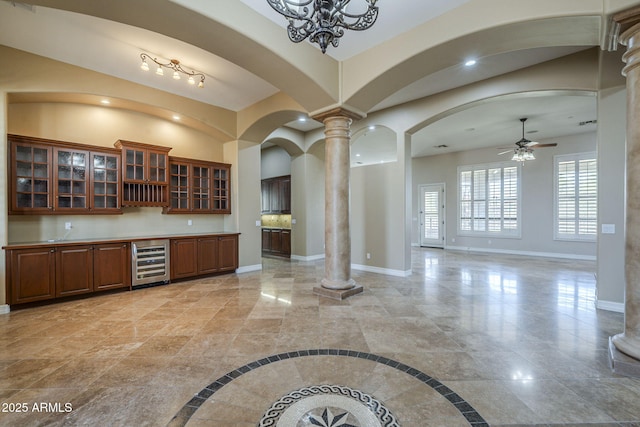 10033 W Jj Ranch Rd, Peoria, AZ 85383 - kitchen featuring wine cooler, decorative columns, baseboards, ceiling fan, and brown cabinetry