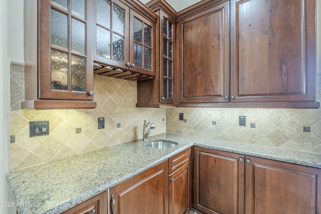 10033 W Jj Ranch Rd, Peoria, AZ 85383 - kitchen featuring a sink, light stone counters, glass insert cabinets, and tasteful backsplash