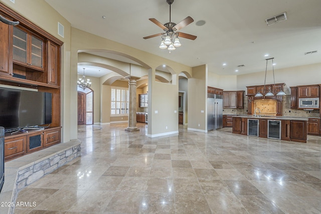 10033 W Jj Ranch Rd, Peoria, AZ 85383 - unfurnished living room with ornate columns, arched walkways, ceiling fan, beverage cooler, and baseboards