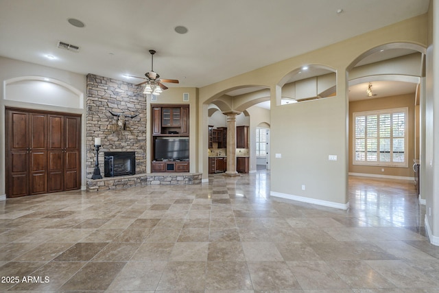 10033 W Jj Ranch Rd, Peoria, AZ 85383 - unfurnished living room with a ceiling fan, arched walkways, baseboards, and a stone fireplace