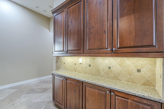 10033 W Jj Ranch Rd, Peoria, AZ 85383 - kitchen featuring baseboards, decorative backsplash, light stone countertops, and arched walkways