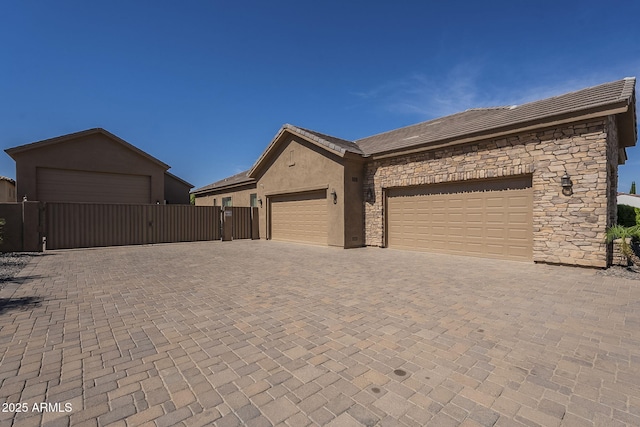 10033 W Jj Ranch Rd, Peoria, AZ 85383 - view of side of property featuring a gate, stone siding, stucco siding, an attached garage, and a tiled roof