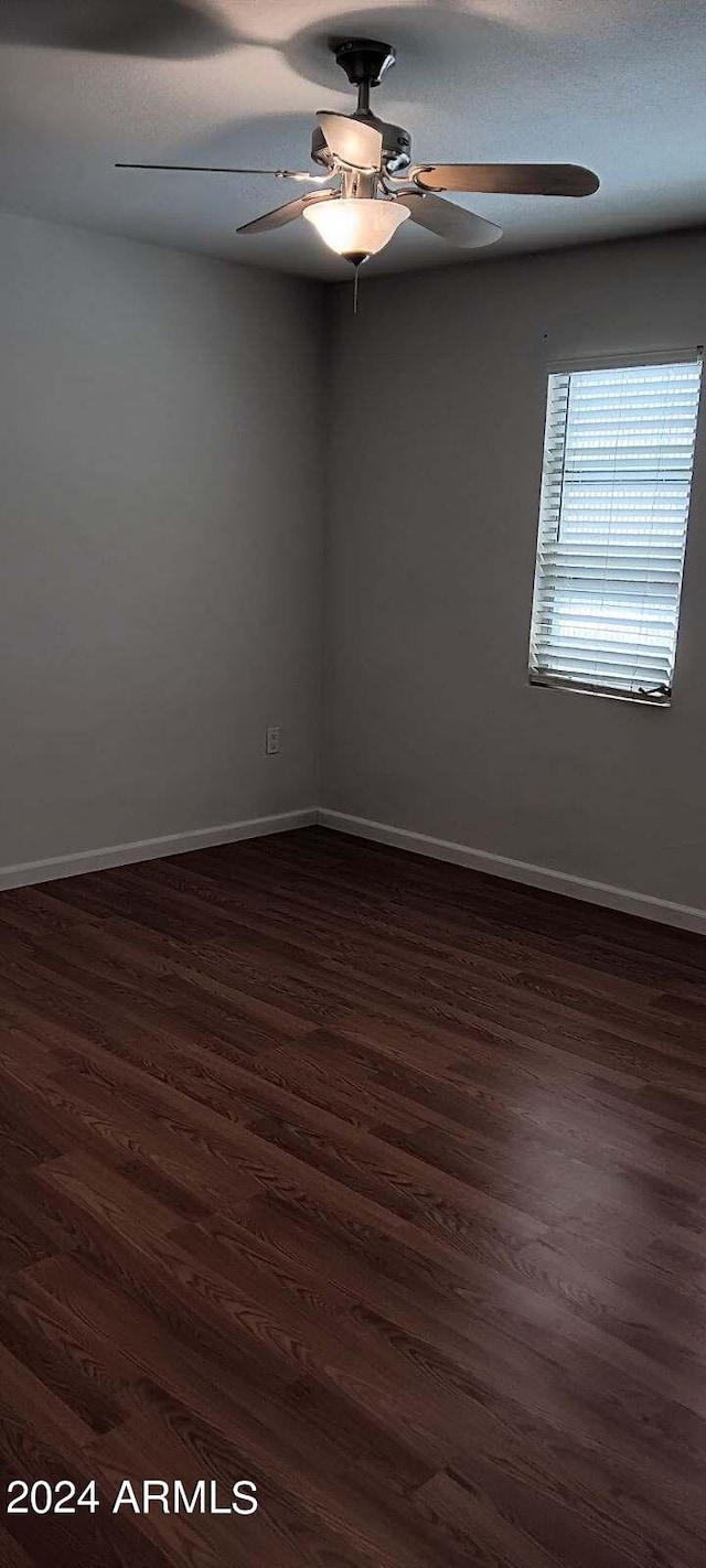 empty room with dark hardwood / wood-style floors and ceiling fan