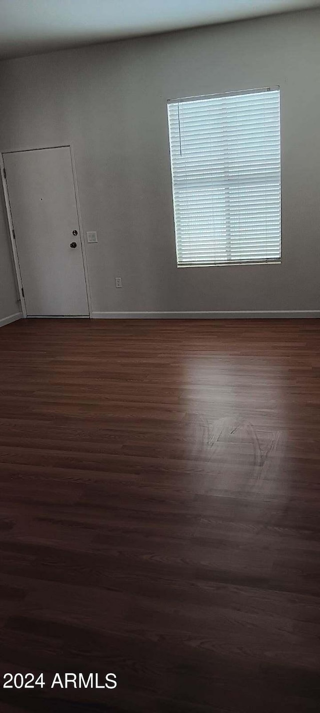 unfurnished room with dark wood-type flooring