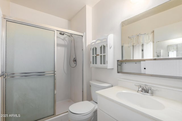 bathroom featuring toilet, a stall shower, and vanity