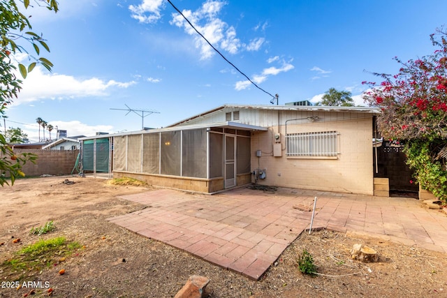 rear view of house featuring a patio, concrete block siding, fence private yard, and a sunroom