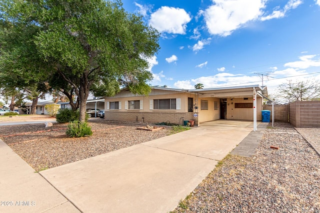 ranch-style house featuring brick siding, an attached carport, driveway, and fence