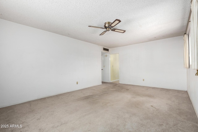 spare room with a ceiling fan, visible vents, carpet floors, and a textured ceiling