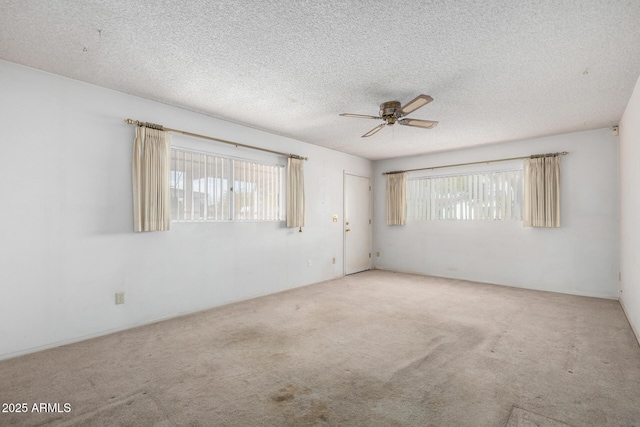 spare room featuring a textured ceiling, plenty of natural light, carpet floors, and ceiling fan