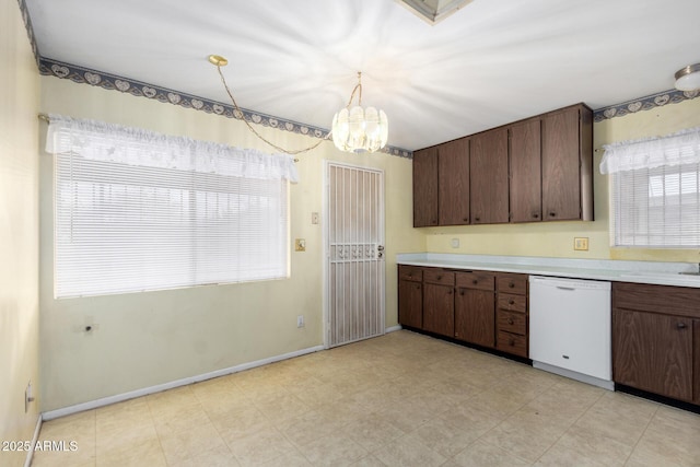 kitchen with a notable chandelier, pendant lighting, white dishwasher, light countertops, and baseboards