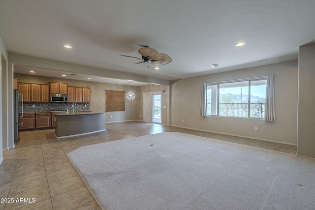 unfurnished living room with light tile patterned floors, sink, and ceiling fan