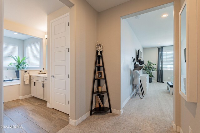 kitchen with stainless steel appliances, decorative light fixtures, a center island with sink, white cabinets, and light wood-type flooring