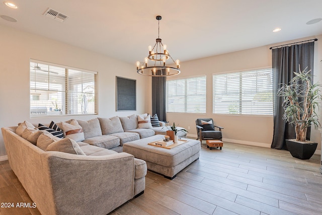 living room with a notable chandelier, plenty of natural light, and light hardwood / wood-style flooring