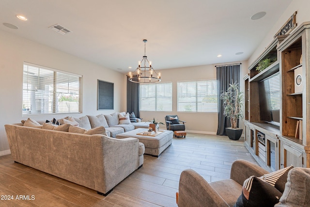 living room featuring light hardwood / wood-style flooring, a healthy amount of sunlight, and a notable chandelier