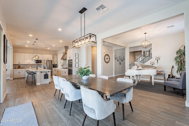 dining space with a notable chandelier, light wood-type flooring, and sink