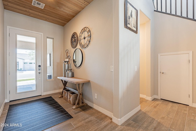 entryway with light wood-type flooring and wooden ceiling