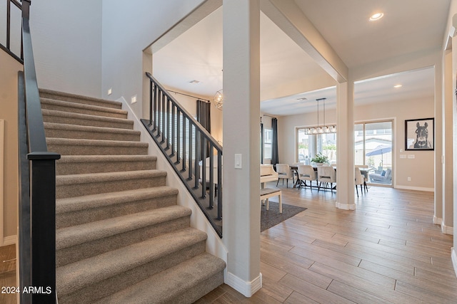 stairs featuring a chandelier and hardwood / wood-style flooring