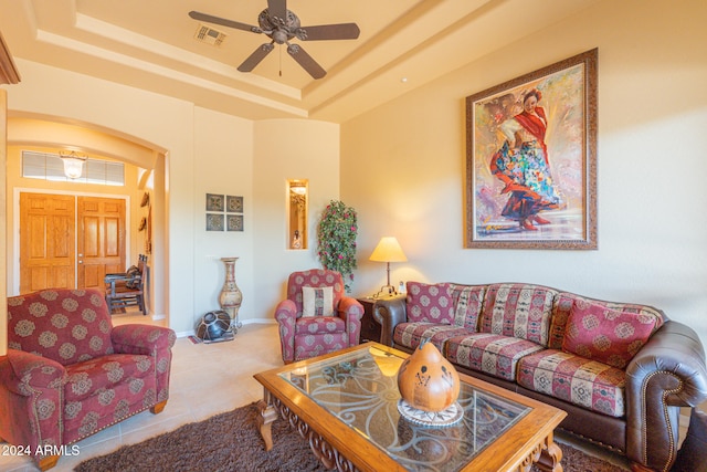 living room featuring ceiling fan, light tile patterned floors, and a raised ceiling