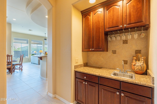 bar featuring sink, light stone countertops, tasteful backsplash, and light tile patterned floors