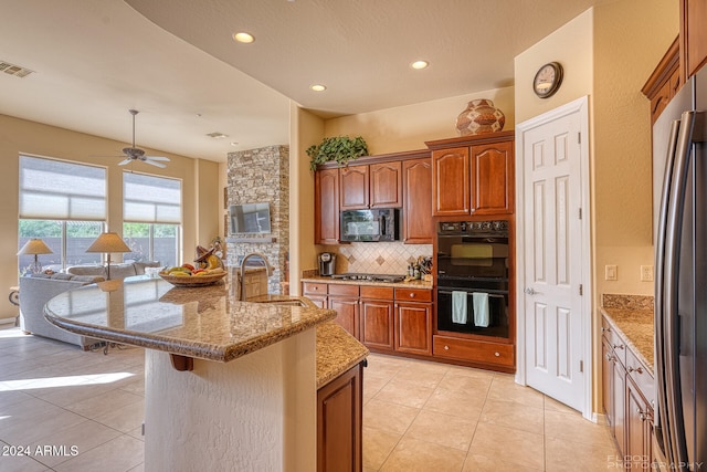 kitchen with light tile patterned floors, an island with sink, a breakfast bar, black appliances, and sink