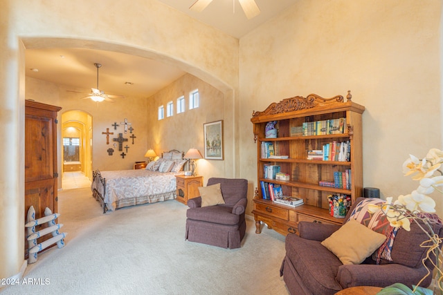 bedroom featuring ceiling fan, light carpet, and a high ceiling