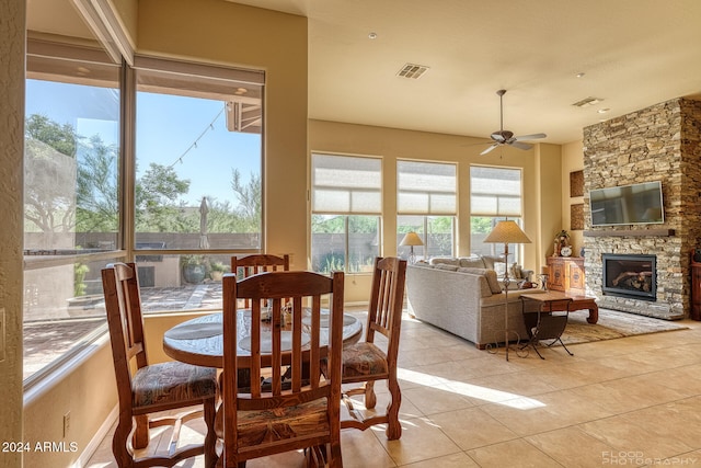 tiled dining room featuring a fireplace and ceiling fan