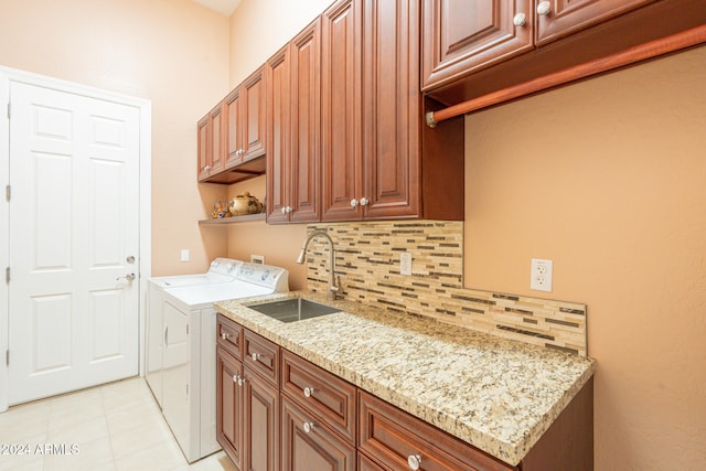 laundry area featuring sink, washer and clothes dryer, light tile patterned floors, and cabinets