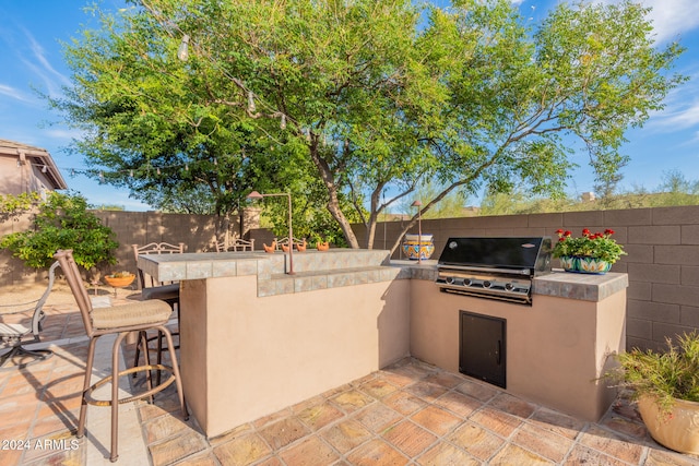 view of patio featuring area for grilling, exterior bar, and an outdoor kitchen