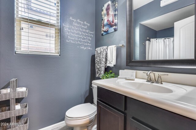 bathroom featuring a shower with shower curtain, toilet, and vanity