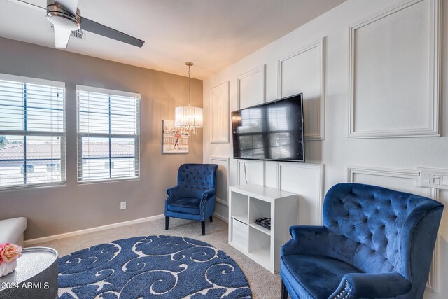 living area featuring ceiling fan with notable chandelier and light carpet