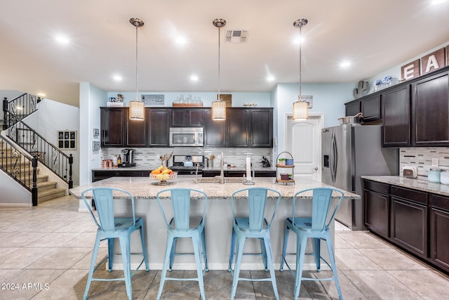 kitchen with hanging light fixtures, light stone countertops, and appliances with stainless steel finishes