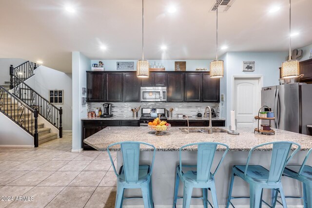 kitchen featuring appliances with stainless steel finishes, pendant lighting, a center island with sink, and sink