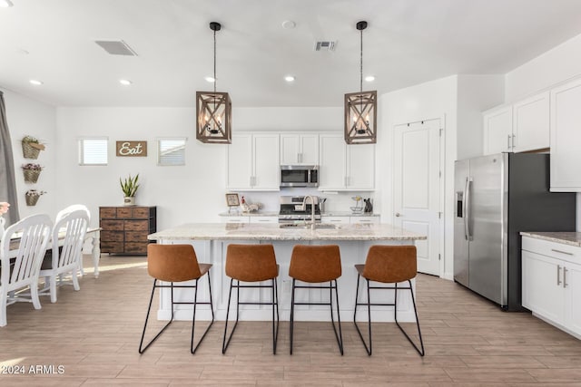 kitchen with a center island with sink, pendant lighting, and appliances with stainless steel finishes