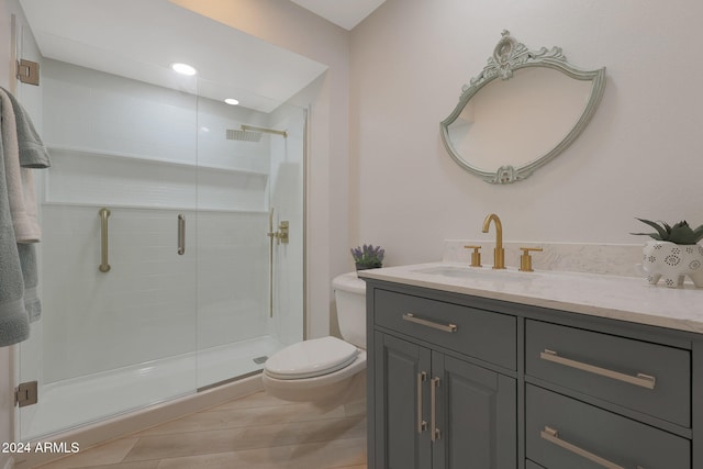 bathroom with vanity, toilet, and a shower with door