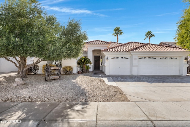 view of front of home with driveway, an attached garage, a tile roof, and stucco siding