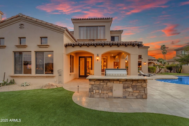 back of property with stucco siding, a fenced in pool, area for grilling, and a patio area